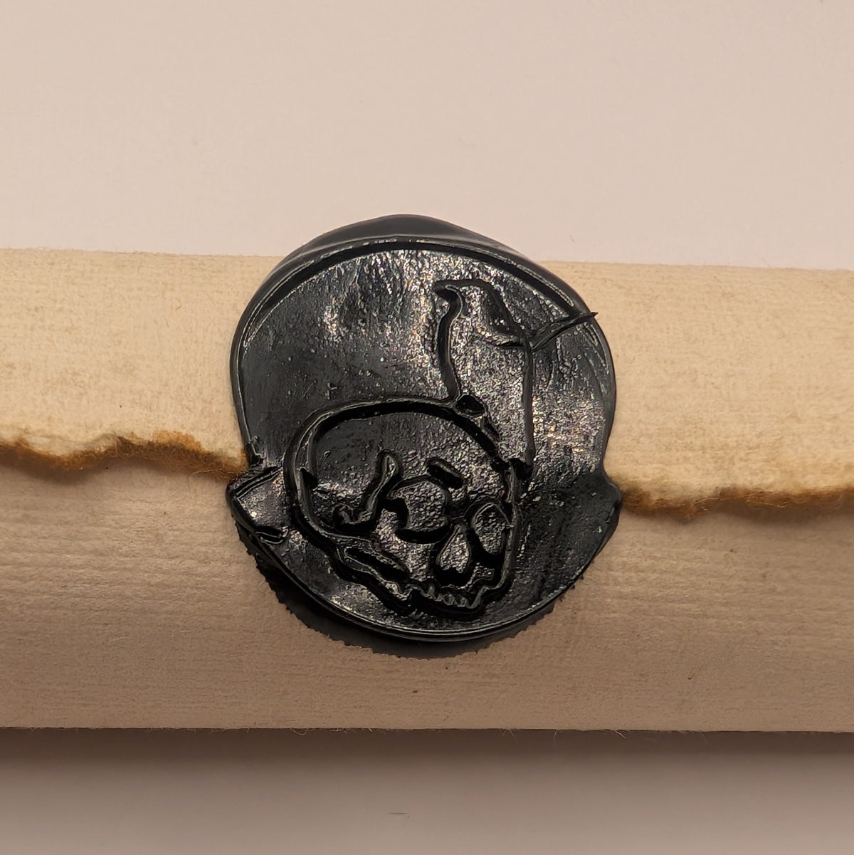 Close-up of the black wax skull and raven seal on a Doom Scroll