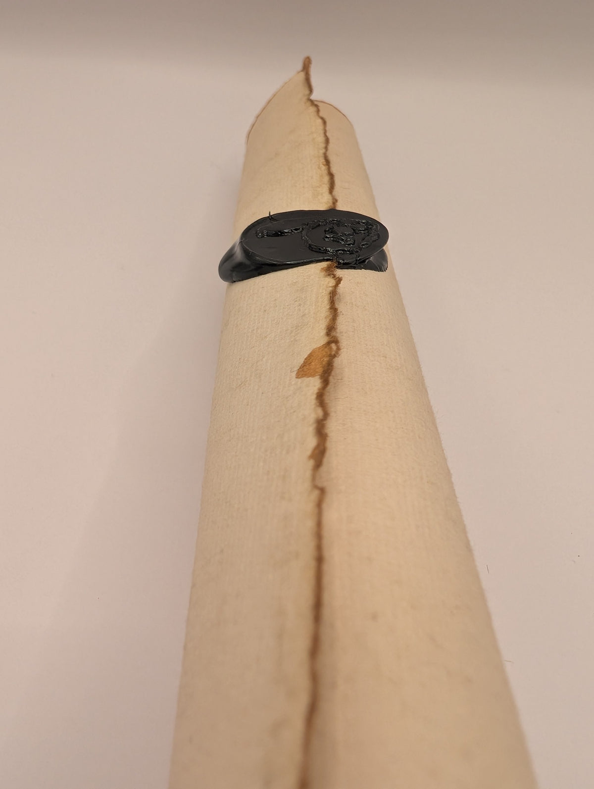 Doom Scroll seen end-on, showing the rolled deckled paper edge and black wax seal