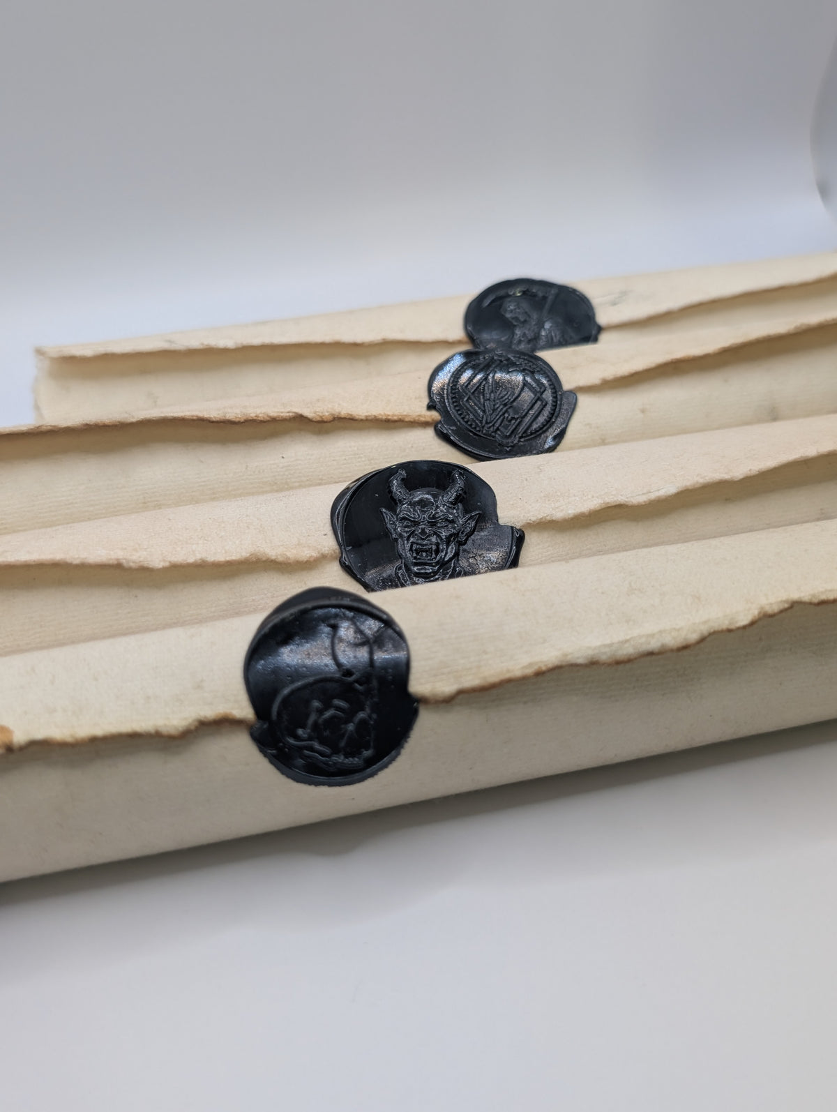 Angled view of four black wax sealed Doom Scrolls stacked together